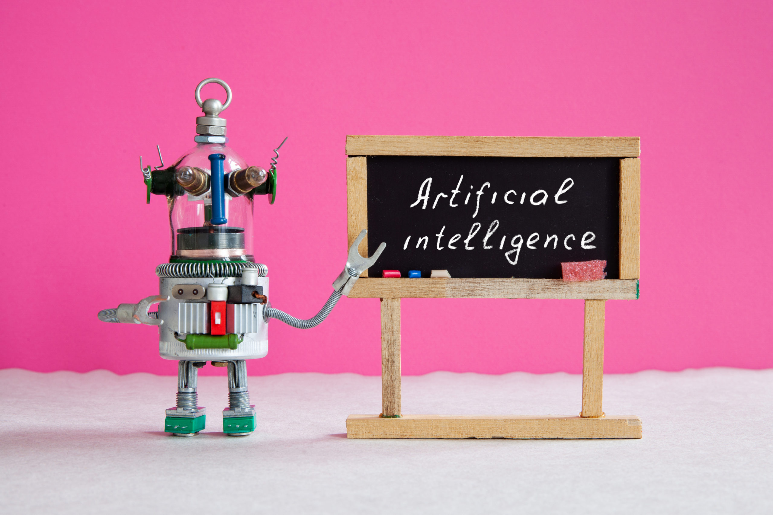 robot next to chalkboard that says 'artificial intelligence'