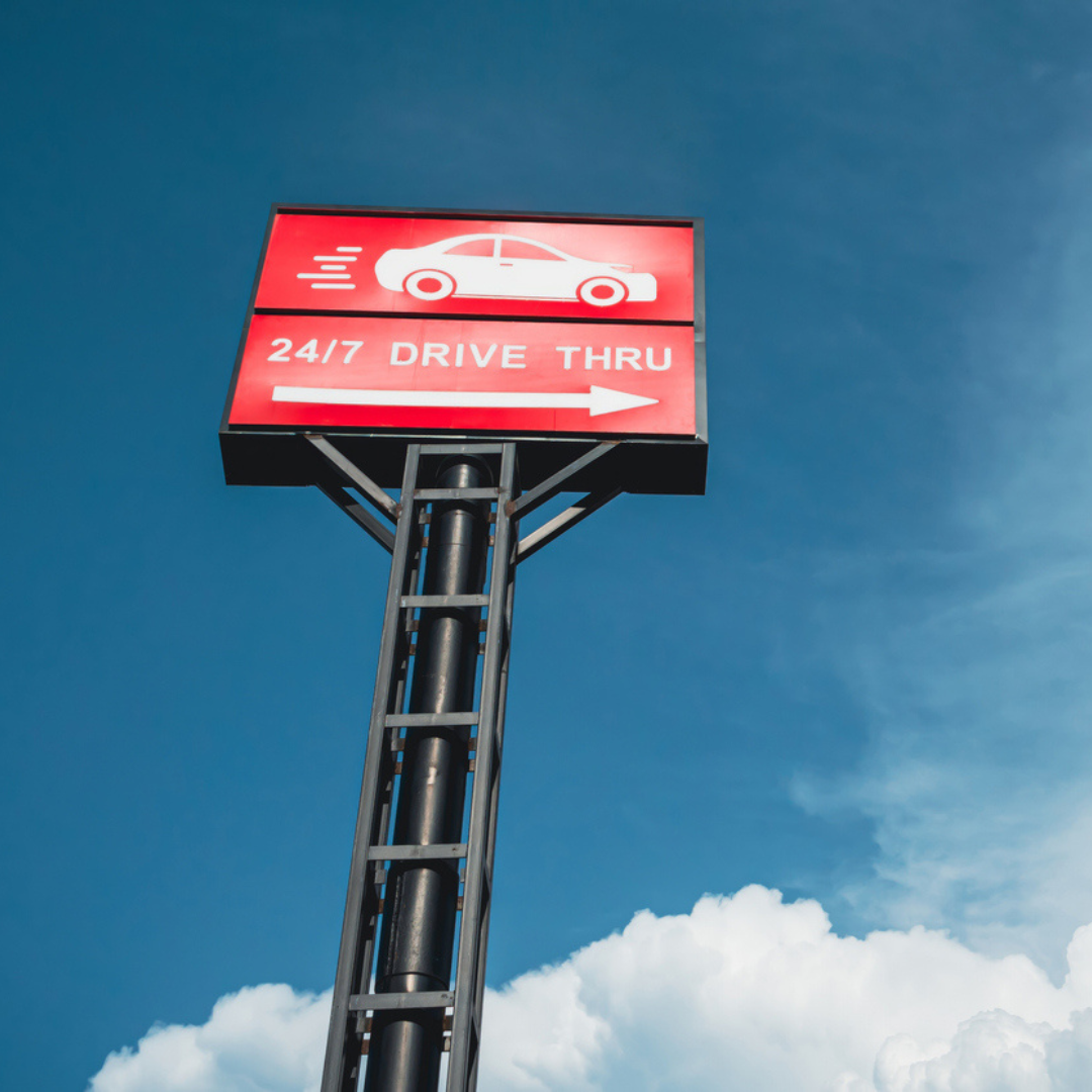 Drive-thru pylon sign towering above a roadway, designed for maximum visibility to passing traffic