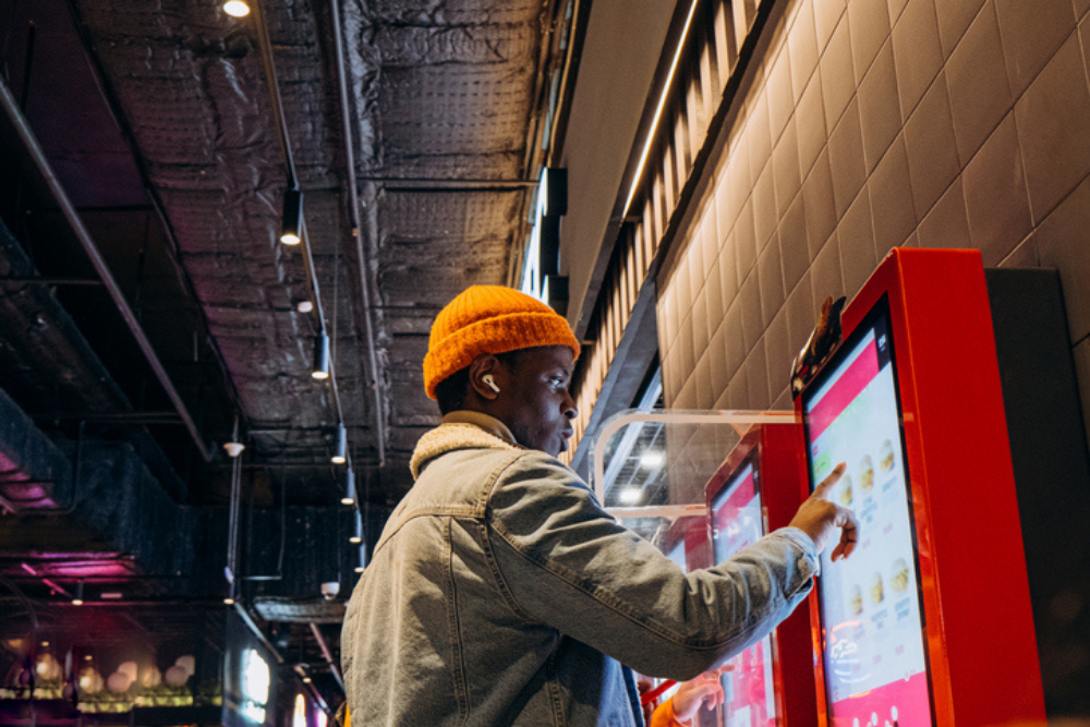Man selects meal of digital menu kiosk